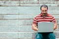 Man sitting on staircase outside and working on laptop Royalty Free Stock Photo