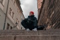 Man Sitting on Stairs in Old European City And Holding Photo Camera. Contemporary Stylish Blogger And Photographer