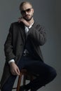 Man sitting on a stool with hand on beard