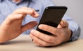 Man sitting at table, holding phone, typing message, searching information, booking or shopping online, studying Royalty Free Stock Photo