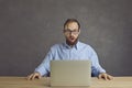 Man sitting at the table with a laptop is very shocked by what he saw on the screen. Royalty Free Stock Photo