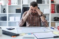 A man is sitting at a table in the office and looks at the graph on a magnetic board.