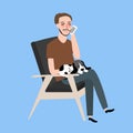 Man sitting together with his cat in vintage chair calling phone