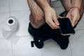 A man is sitting on the toilet with a phone in his hand. Guy& x27;s morning routine Royalty Free Stock Photo