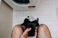 A man is sitting on the toilet with a phone in his hand. Guy& x27;s morning routine Royalty Free Stock Photo