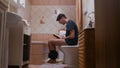 A man sitting on the toilet and reading a book