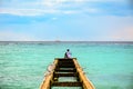 A man sitting on top of a pier surrounded by seagulls observes t