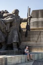 Man sitting under a gigantic Communist statue in the museum of the Great Patriotic war
