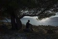 Man sitting under tree in shadow close the ocean at sunset Royalty Free Stock Photo