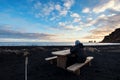 A man sitting on wooden bench at Black Sand Beach in sunset