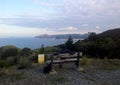 Man sitting on a wooden bench and enjoying the view of the Great barrier island`s landscape, palmers lookout