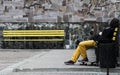 Man Skateboarder relaxing on bench. Yellow bench and stone background. Lifestyle Relax Hipster Concept Royalty Free Stock Photo