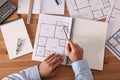 Man with sketchbook and pencil at wooden table, top view