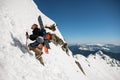 Man ski-climber with backpack and ski equipment climbing at snowy ridge