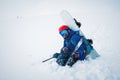 man with ski equipment and a snowboard is sitting a snowy mountain. Blue sky and snowy mountain in the background. Royalty Free Stock Photo