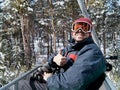 Man skier on chairlift in forest