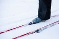 Man is skiing. Close-up of legs in gray ski boots on skis, man riding in snow on clear sunny day, side view