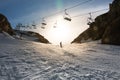 A man skiing down a slope passing under a ski lift in backlit Royalty Free Stock Photo