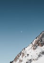 a man skiing down a steep mountain side in winter, with the moon over him Royalty Free Stock Photo