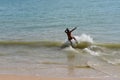 Man on a skimboard catching a wave in a beach in Aonang, Krabi, Thailand