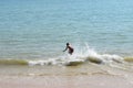 Man on a skimboard catching a wave in a beach in Aonang, Krabi, Thailand Royalty Free Stock Photo