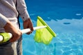 Man with skimmer net equipment cleaning swimming pool from rubbish. Service and maintenance of the pool. Male removes Royalty Free Stock Photo