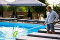 Man with skimmer net equipment cleaning swimming pool from rubbish. Service and maintenance of the pool. Male removes Royalty Free Stock Photo