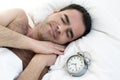 Man sleeping in bed with alarm clock