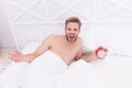 Man sleeping bed white bedclothes and red alarm clock, feeling irritated concept Royalty Free Stock Photo