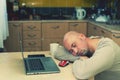 Man sleeping on the table with laptop at home. bald man sleeping at his working place home office. Portrait of a man lying down at Royalty Free Stock Photo