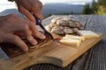 Man slice up delicious South Tyrolean smoked bacon and cheese with flat bread lying on a rustic table Royalty Free Stock Photo