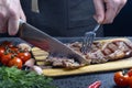 A man slices a steak chuck roll. The meat is medium rare Royalty Free Stock Photo