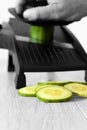 Man slicing cucumber with a mandoline on a grey wood kitchen worktop Royalty Free Stock Photo