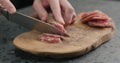 Man slicing fuet sausage on olive wood board