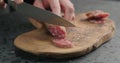 Man slicing fuet sausage on olive wood board