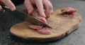 Man slicing fuet sausage on olive wood board