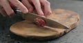 Man slicing fuet sausage on olive wood board