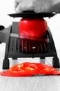 Man slicing red pepper with a mandoline on a grey wood kitchen worktop Royalty Free Stock Photo
