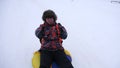 Man slides slide in snow on an inflatable snow tube and waves hand. Happy men slides through snow on sled. men playing