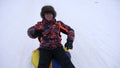 Man slides slide in snow on an inflatable snow tube and waves hand. Happy men slides through snow on sled. men playing