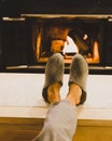 Man in slippers relaxing with his feet up with a fireplace in the background. Royalty Free Stock Photo