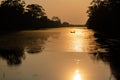 a lone man in a small boat at sunset along the river Royalty Free Stock Photo