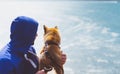 Man with small golden japanese shiba inu dog sitting togetherness on a mountain and looking at blue sea horizon, friends on relax Royalty Free Stock Photo