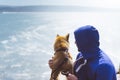 Man with small golden japanese shiba inu dog sitting togetherness on a mountain and looking at blue sea horizon, friends on relax Royalty Free Stock Photo