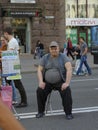 Man small-time con man sitting on the chair on the street offering people passing by to measure bioelectrical currents