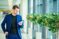 Man with smart phone inside in airport. Casual young boy wearing suit jacket. Caucasian man with cellphone at the Royalty Free Stock Photo