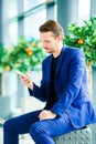 Man with smart phone inside in airport. Casual young boy wearing suit jacket. Caucasian man with cellphone at the Royalty Free Stock Photo