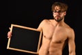 Man smart and with beard and tousled hair wears eyeglasses. Macho attractive nude guy hold blackboard. Man