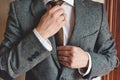 Man in smart suit wearing wedding ring adjusting tie