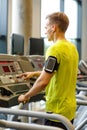 Man with smartphone exercising on treadmill in gym Royalty Free Stock Photo